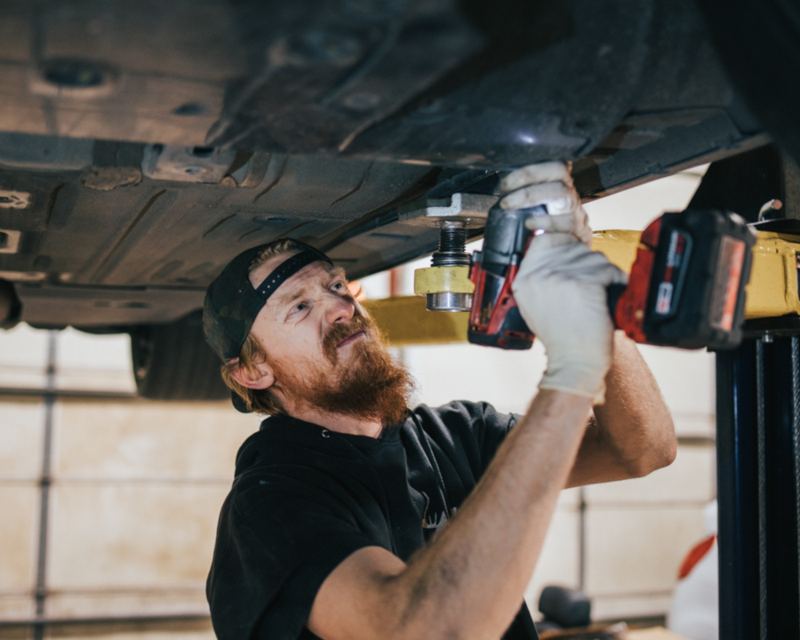 William working under a car on a lift